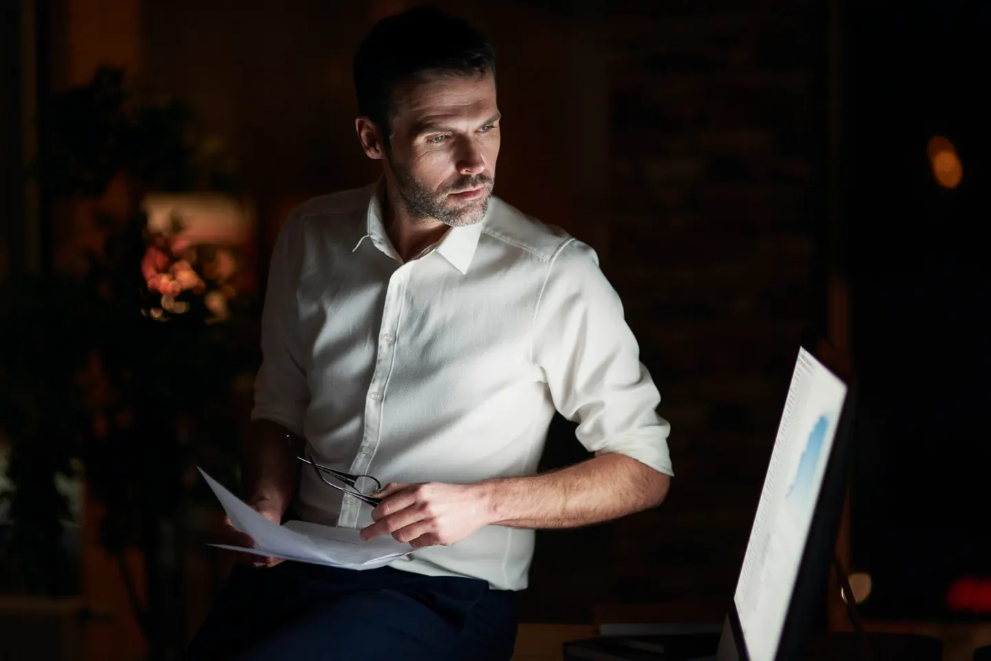 Professional reviewing documents beside a laptop
